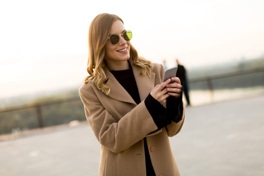 View at modern woman using mobile phone at autumn outdoor