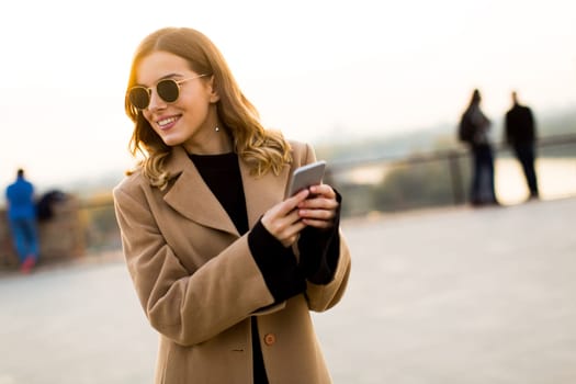 Portrait of young woman with eyeglasses with mobile phone outdoor
