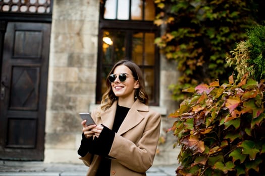 View at modern woman using mobile phone at autumn outdoor