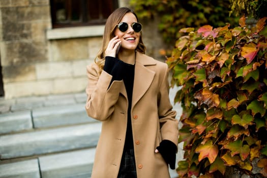 View at modern woman using mobile phone at autumn outdoor