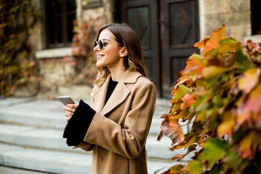 View at modern woman using mobile phone at autumn outdoor