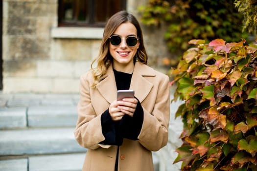 Portrait of young woman with mobile phone at autumn outdoor