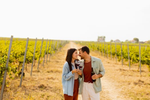 Under the warm glow of the setting sun, a couple shares laughter while sipping wine in a picturesque vineyard, creating cherished memories amid rows of grapevines