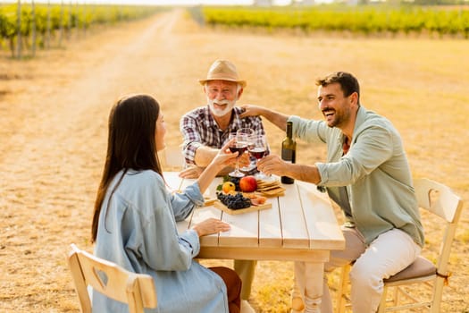 Amidst rows of lush vines, three friends enjoy a delightful afternoon, savoring wine and conversation, surrounded by the beauty of nature’s harvest