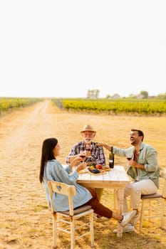Amidst rows of lush vines, three friends enjoy a delightful afternoon, savoring wine and conversation, surrounded by the beauty of nature’s harvest