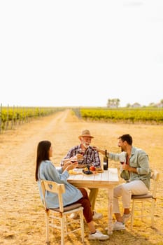 Amidst rows of lush vines, three friends enjoy a delightful afternoon, savoring wine and conversation, surrounded by the beauty of nature’s harvest