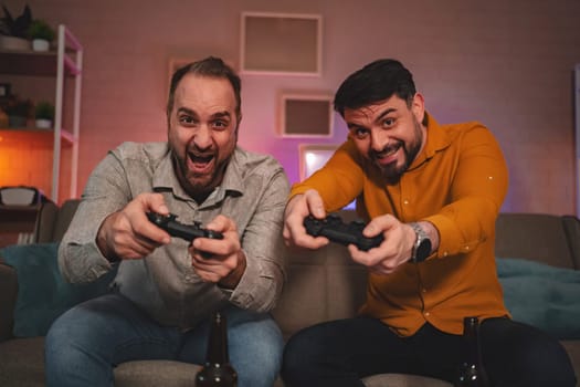 Two friends immerse themselves in an exciting gaming session, controllers in hand, laughter filling the cozy lounge. Their cheerful expressions reflect the joy of friendly competition.