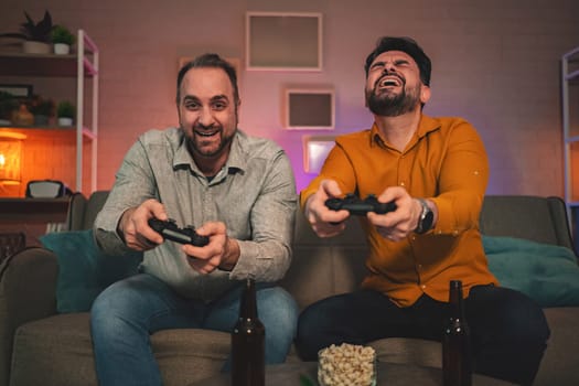 In a comfortable and inviting living room, two friends are deeply engaged in a thrilling gaming session. With joy on their faces, they hold controllers tightly, surrounded by snacks and drinks.