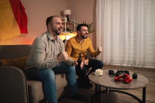 Friends gather in a cozy living room, cheering and celebrating as they watch an intense sports match together. Their joy radiates, enhanced by snacks and drinks.