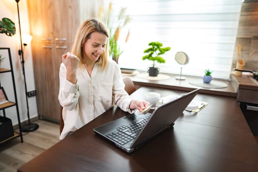 Excited woman beams with joy after achieving a work milestone at home.