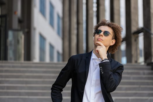 Portrait of Caucasian puzzled businessman professional standing outdoors deep in thoughts thinking recollecting memory creating plan. Handsome man in formalwear and sunglasses on downtown city street.