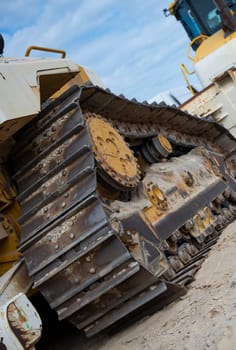 Heavy machinery is positioned along the sandy coastline, actively involved in erosion control and coastal protection efforts under a cloudy sky.
