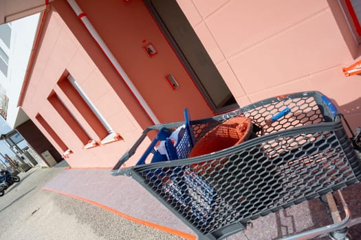 A paint roller rests in a bucket filled with reddish-brown paint. Surrounding tools and a work environment indicate ongoing home improvement activities in good weather.