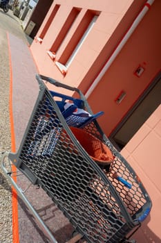 A paint roller rests in a bucket filled with reddish-brown paint. Surrounding tools and a work environment indicate ongoing home improvement activities in good weather.