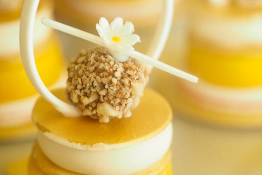 A small dessert topped with nuts and a flower, displayed at a bakery.