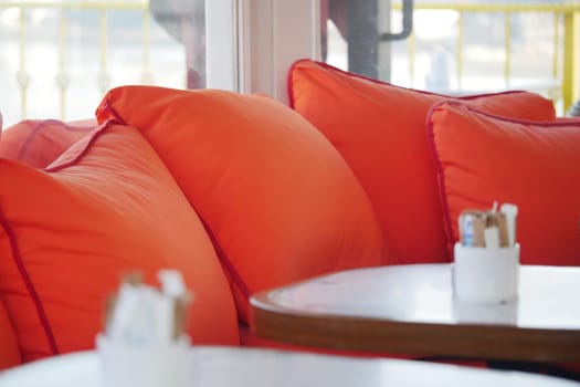 Bright orange cushions adorn the seating in a cozy cafe, inviting relaxation.