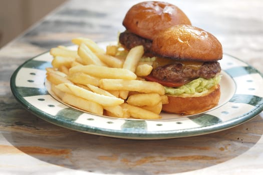 Two stacked cheeseburgers with fries are ready to enjoy for lunch.
