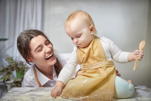 A family enjoys a fun cooking session, playfully covered in flour while engaging with their little ones in warm kitchen. Mother and child having fun