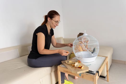 Mom and daughter sharing a moment feeding their pet bird some fruit