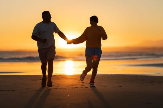 Couple running on the beach at sunset holding hands