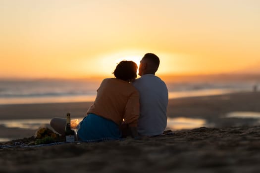 Couple sharing intimate moment during sunset picnic on the beach