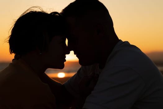 Silhouette of loving couple touching foreheads during romantic sunset on beach