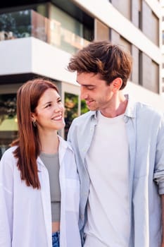 young man and woman smiling happy to each other while talking in a romantic walk down street, concept of couple and urban lifestyle