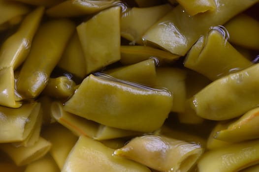 Bright green slices of pickled vegetables rest in a tangy brine, ready to enhance any dish with their crunch and flavor.