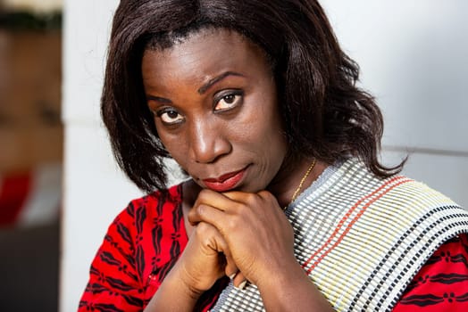 beautiful adult businesswoman dressed in red plaid loincloth sitting holding her hands on her chin while looking in profile.