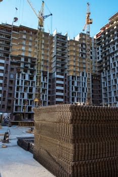 Ongoing construction of modern high-rise apartments with cranes, steel reinforcements, and unfinished structures.