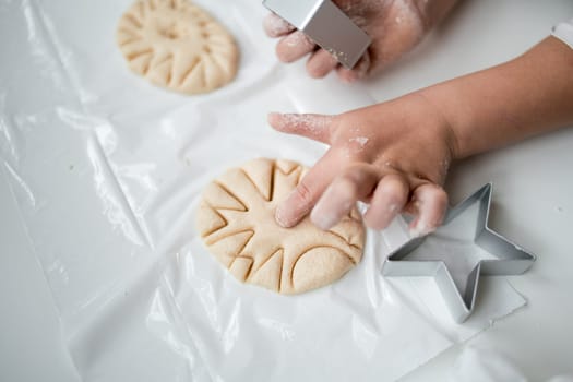 Child crafting star shaped dough with cookie cutter.