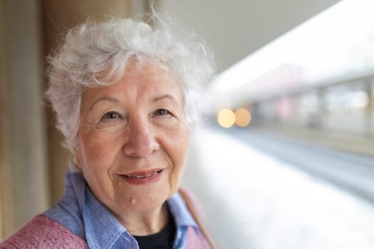 Close-up of happy elderly woman with gray hair smiling while standing in train station