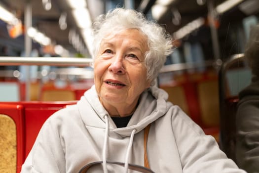 Happy elderly woman commuting on a subway train, enjoying her journey