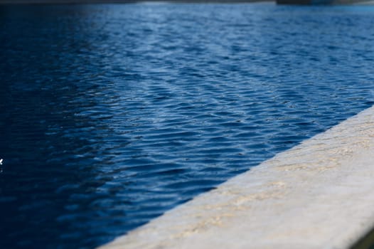 Gentle waves lap at a clear pool, reflecting sunlight and surrounding beauty in peaceful harmony.