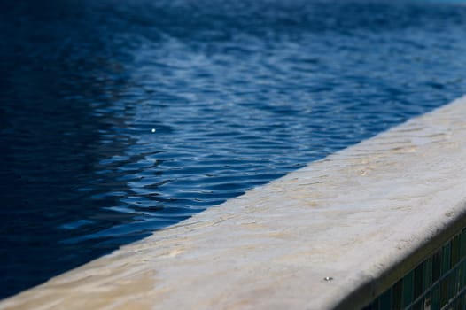Soft ripples dance on the water's surface as sunlight warms the tranquil poolside, creating a peaceful atmosphere.