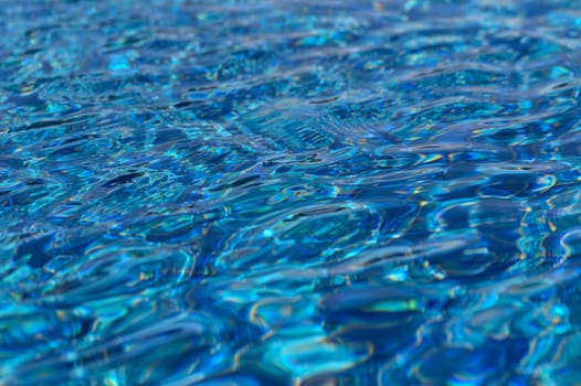 Sunlight glimmers on the surface of a tranquil swimming pool, creating enchanting patterns of blue and aqua.