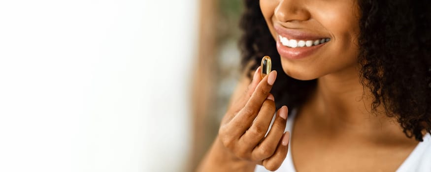 Beauty Supplement. Closeup Of Smiling Black Woman Taking Vitamin Pill Capsule, Having Diet Nutrition, Cropped Image
