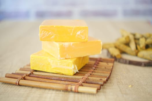 Yellow cheese blocks are stacked on a bamboo tray with snacks nearby.