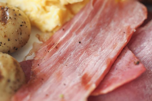 A close-up view of a breakfast platter with eggs and sliced meats.