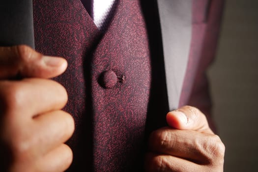 A well-dressed person adjusts their burgundy jacket, radiating style.
