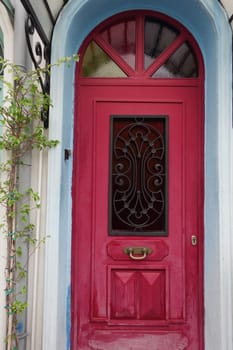 A vibrant red door features a decorative grill in a quaint neighborhood.