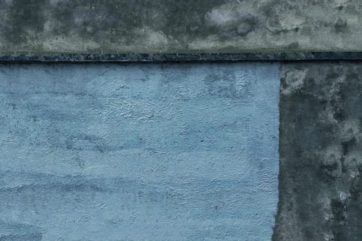 Old concrete wall covered with blue paint, painting work. Unfinished gray wall.