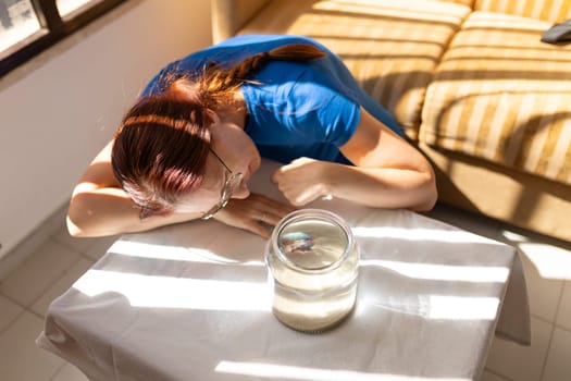 Woman lying on a table and watching a blue fighting fish in a jar