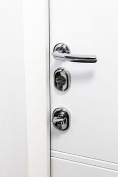 White door with metal handle and locks as a part of interior design
