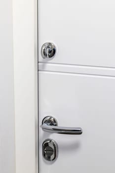White door with metal handle and locks as a part of interior design