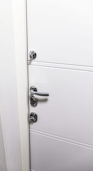 White door with metal handle and locks as a part of interior design