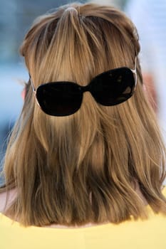 A humorous and innovative image of long hair with sunglasses, transforming the back of a head into a funny visual trick, ideal for creative projects.