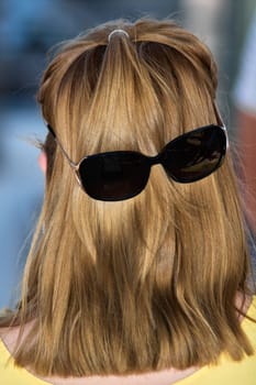 Back view of long hair with sunglasses placed on it, forming an amusing and creative face illusion, perfect for quirky design projects.