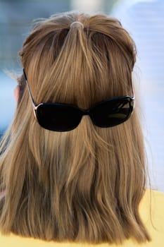 Long hair styled creatively with sunglasses positioned on the back, forming an entertaining face illusion, great for humorous concepts.