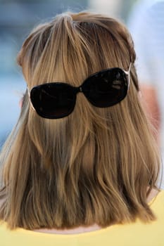 Unique and playful visual of hair and sunglasses, forming a face on the back of a head, perfect for capturing creative moments.